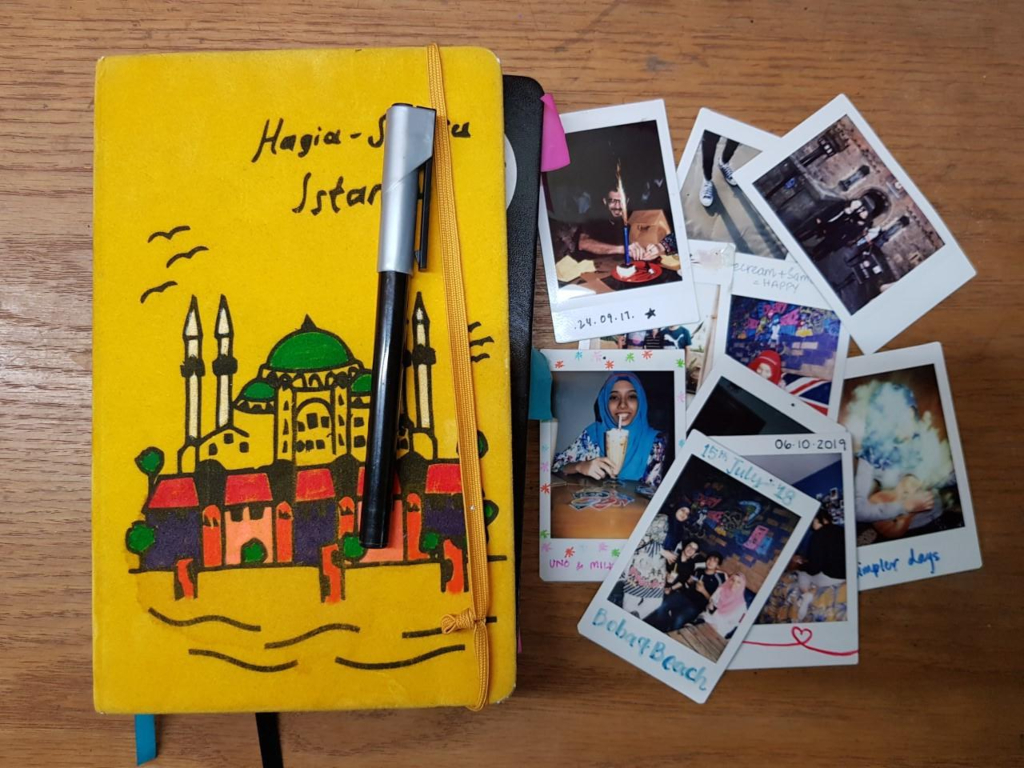 Yellow notebook with polaroid photographs next to it