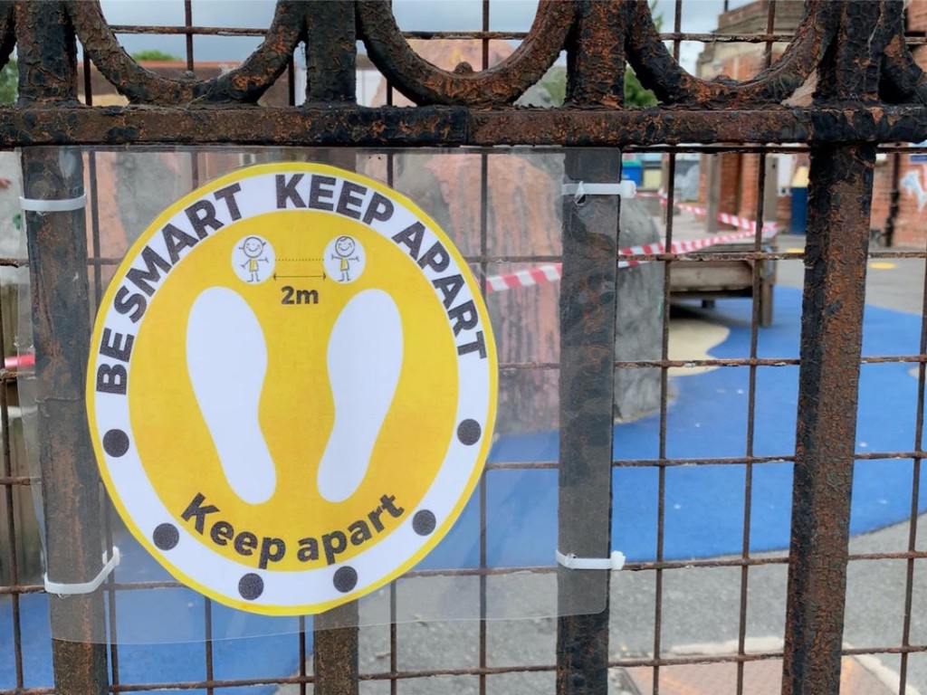 A sign attached to a gate that says 'Be smart, keep apart'