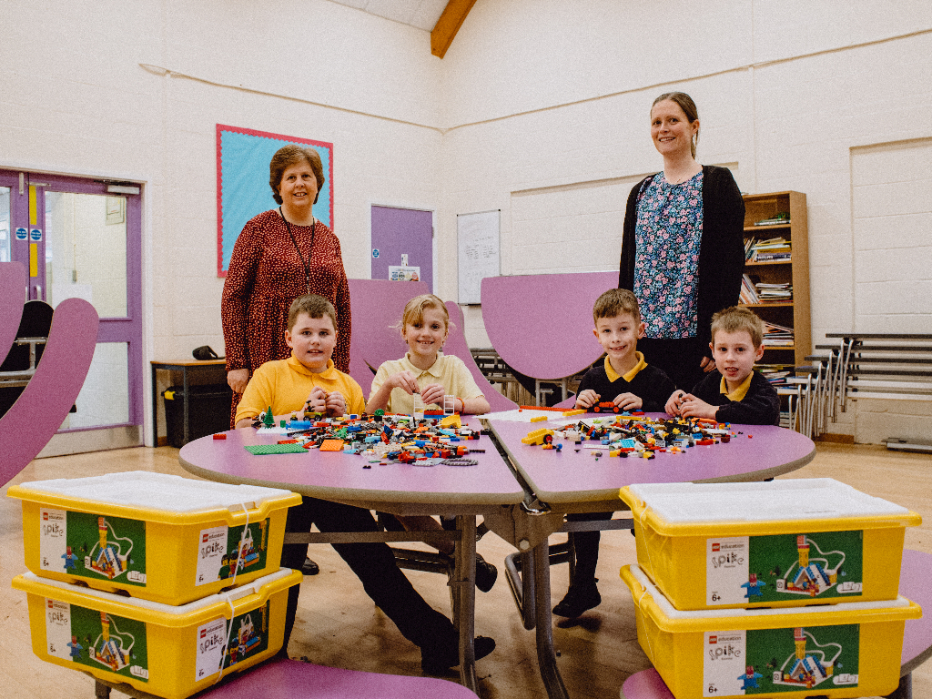 Reculver School pupils playing with LEGO with a teacher and Beaney member of staff standing behind them